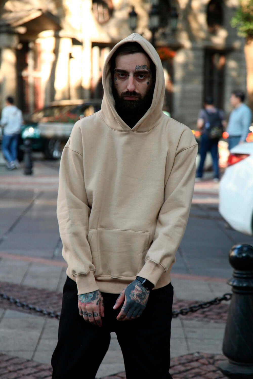 A person wearing a plain multi colored hoodies in a city setting with a casual street style.