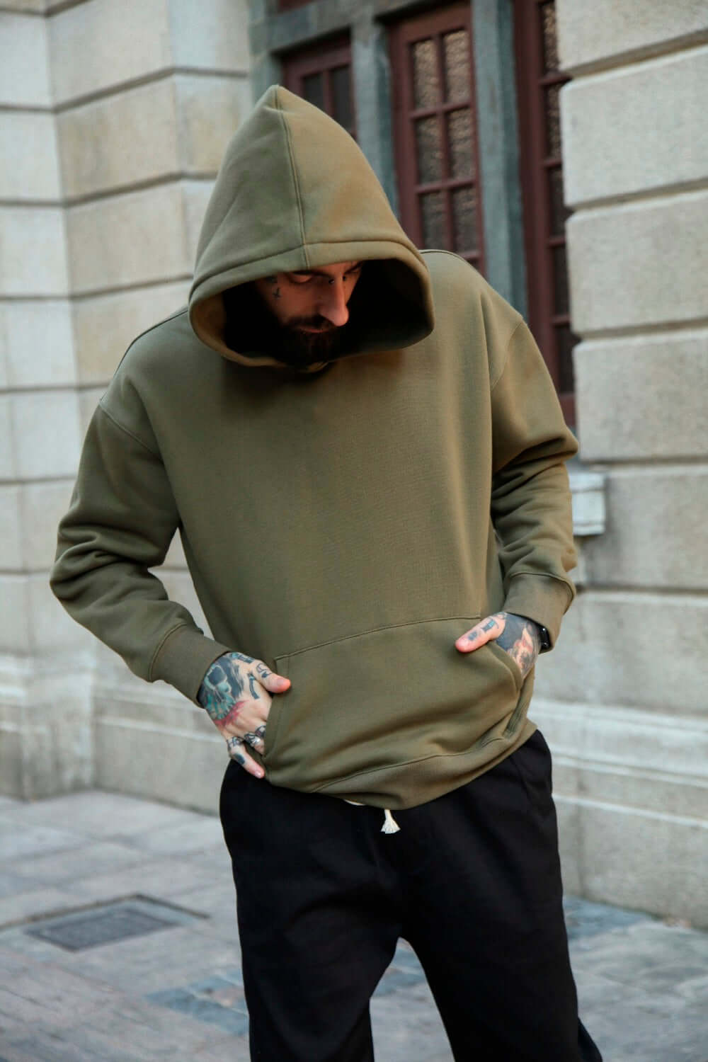 Plain multi colored hoodies displayed on a model in a stylish urban setting with tattoos.