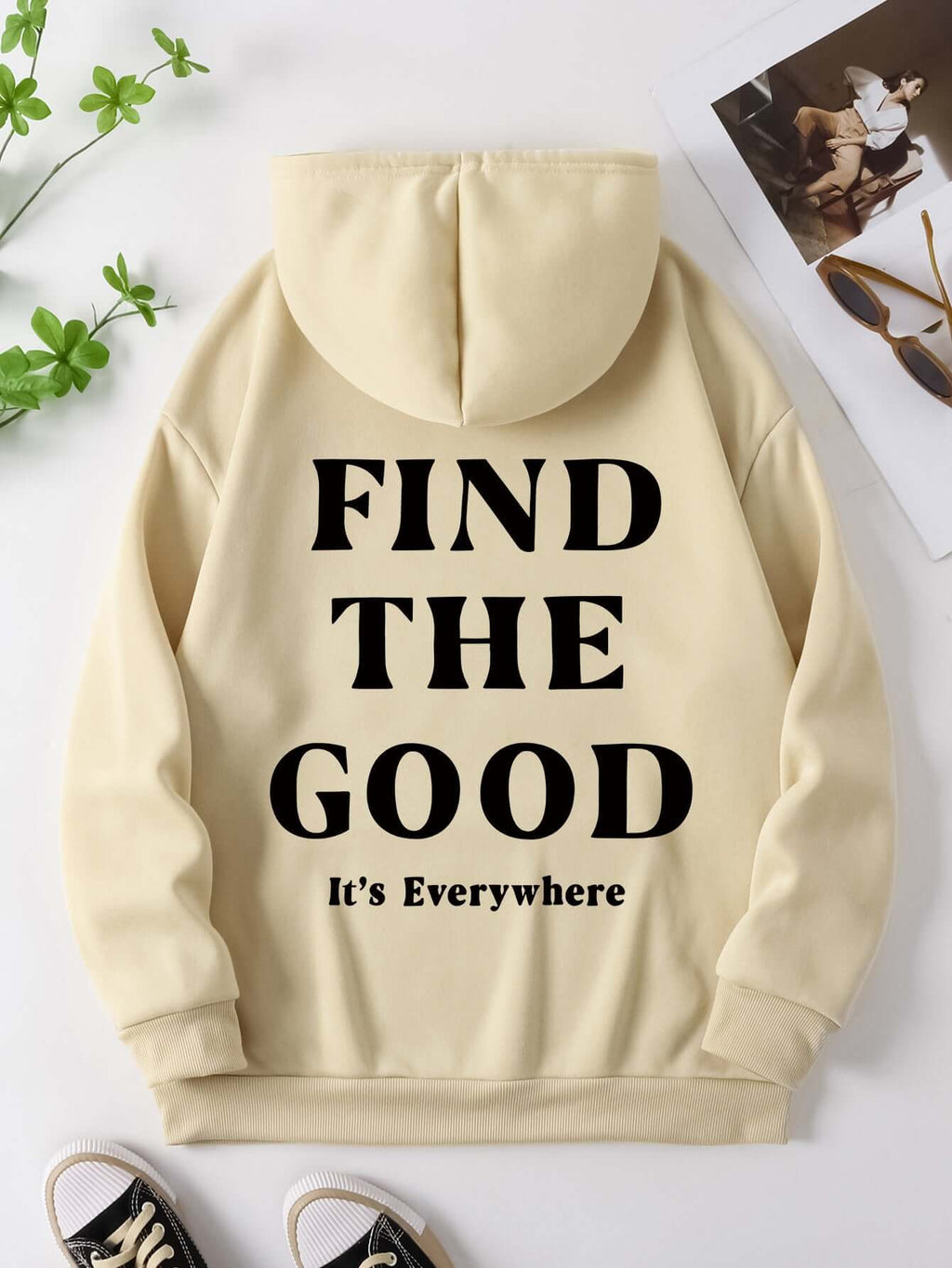 Brushed hoodie in light beige with black text saying 'FIND THE GOOD It's Everywhere' on the back.